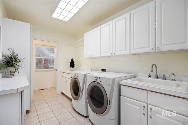 laundry area with sink, light tile patterned floors, cabinets, and washer and clothes dryer