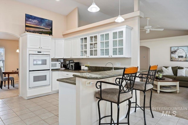 kitchen featuring kitchen peninsula, white cabinetry, light tile patterned floors, and white appliances