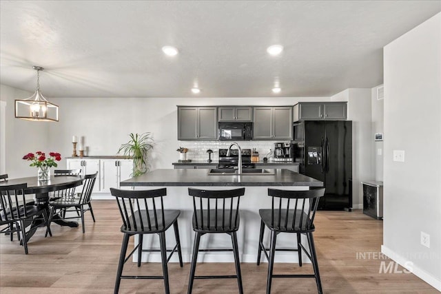 kitchen with dark countertops, a sink, black appliances, and a breakfast bar area