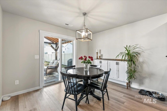 dining area with light wood finished floors, baseboards, and visible vents