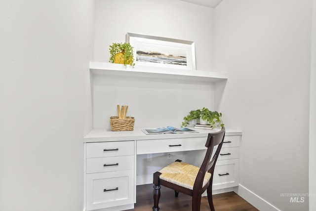 office space featuring baseboards, dark wood-type flooring, and built in desk