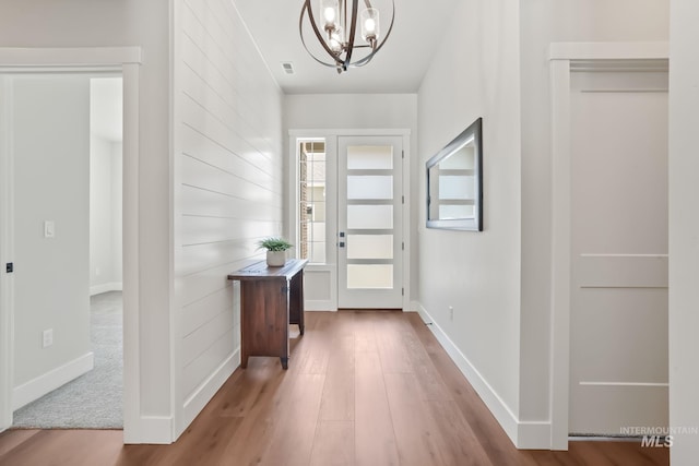 entrance foyer featuring visible vents, baseboards, a notable chandelier, and wood finished floors