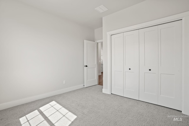 unfurnished bedroom with a closet, baseboards, light colored carpet, and visible vents