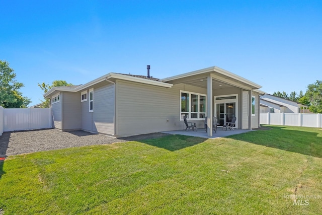 back of property with a yard, a fenced backyard, and a patio area
