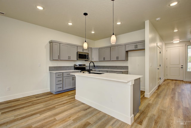 kitchen with a sink, stainless steel appliances, gray cabinetry, and light countertops