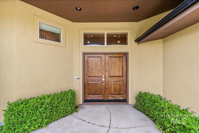 view of exterior entry featuring stucco siding and french doors