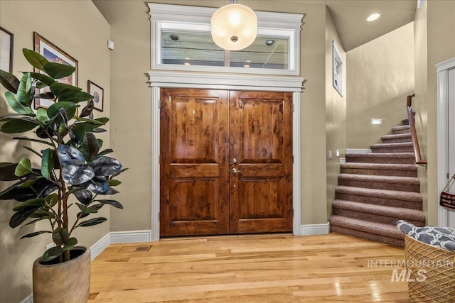 entryway featuring stairs, baseboards, and light wood-style floors