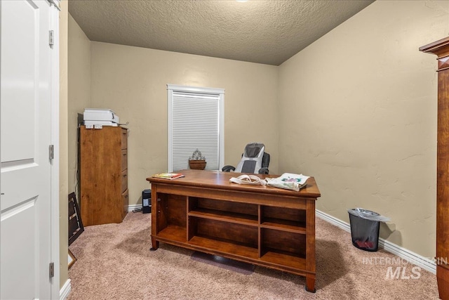 office space with a textured ceiling, light carpet, and baseboards