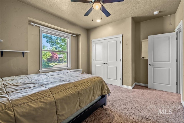 carpeted bedroom with a closet, a textured ceiling, and a ceiling fan