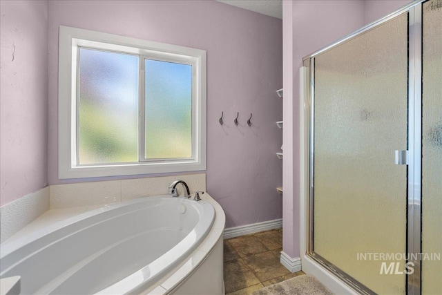 bathroom with a garden tub, baseboards, and a stall shower