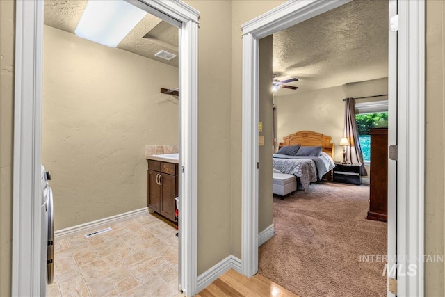 bathroom featuring vanity, a textured ceiling, baseboards, and visible vents
