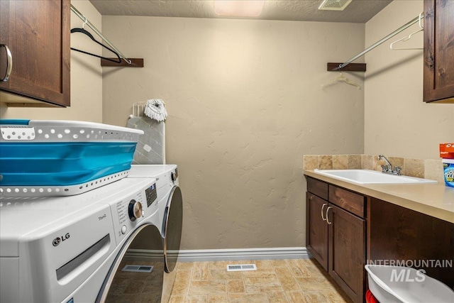 laundry room featuring a sink, cabinet space, separate washer and dryer, visible vents, and baseboards