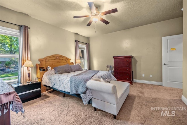 carpeted bedroom with a textured ceiling, baseboards, and a ceiling fan