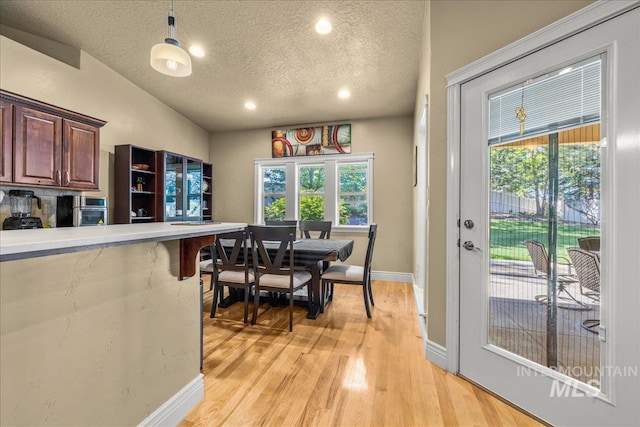 dining area featuring light wood finished floors, a textured ceiling, baseboards, vaulted ceiling, and recessed lighting