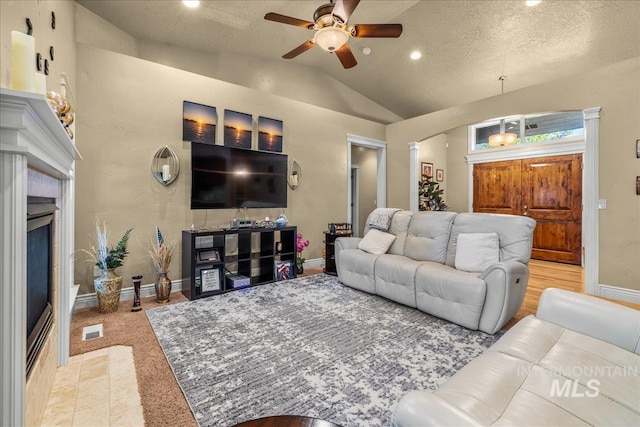 living room with lofted ceiling, visible vents, a fireplace, ceiling fan, and baseboards