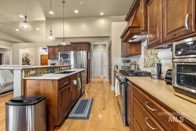 kitchen with a sink, stainless steel appliances, decorative backsplash, and an island with sink