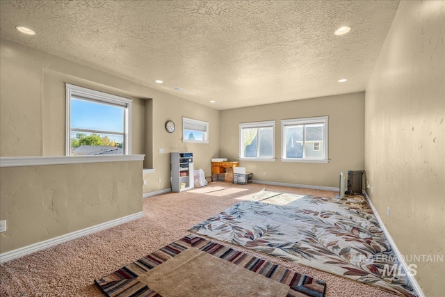 interior space featuring a textured ceiling, carpet, baseboards, and recessed lighting
