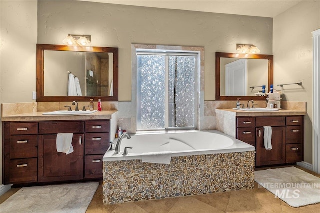 full bathroom featuring a bath, tile patterned flooring, two vanities, and a sink