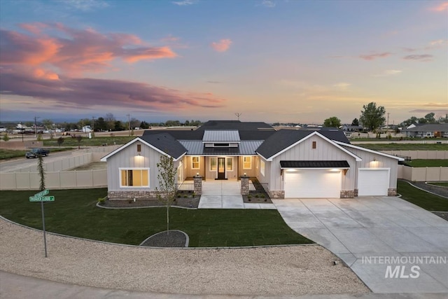 modern inspired farmhouse with covered porch, a yard, and a garage