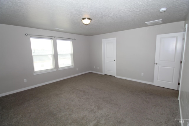 carpeted spare room with visible vents, a textured ceiling, and baseboards