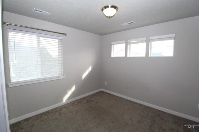 carpeted spare room featuring baseboards and visible vents