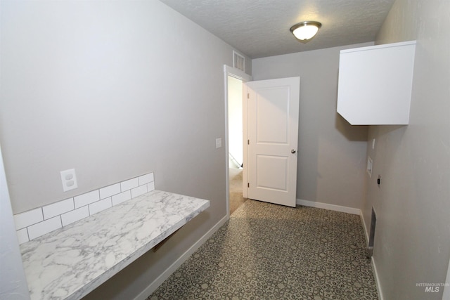 interior space with visible vents, baseboards, and a textured ceiling