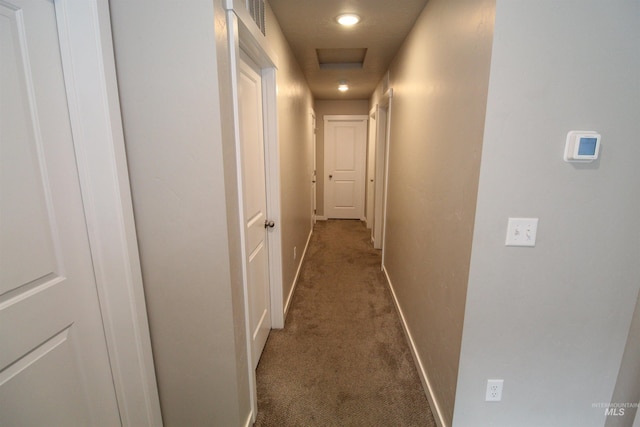 hallway featuring visible vents, dark colored carpet, attic access, and baseboards