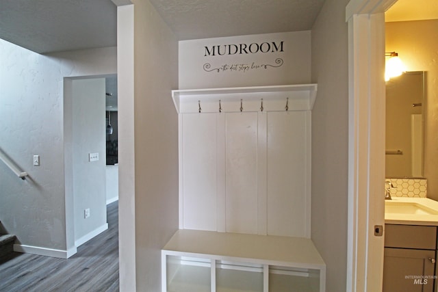 mudroom featuring baseboards, a sink, and wood finished floors