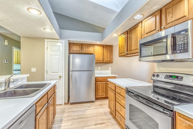 kitchen featuring stainless steel appliances, vaulted ceiling, light hardwood / wood-style floors, and sink