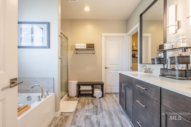 full bathroom featuring separate shower and tub, vanity, wood-type flooring, and toilet