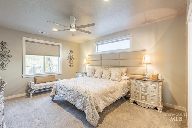 bedroom with ceiling fan, carpet floors, and a textured ceiling