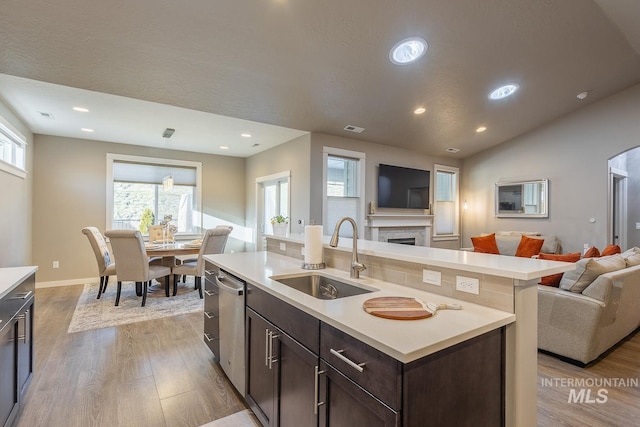 kitchen with light wood-type flooring, dishwasher, a center island with sink, and sink