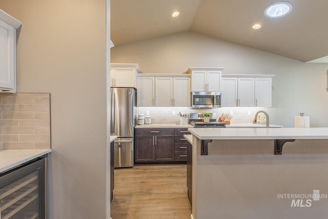 kitchen featuring backsplash, white cabinets, stainless steel appliances, and a breakfast bar area