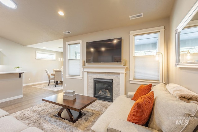 living room featuring light hardwood / wood-style floors and a tiled fireplace