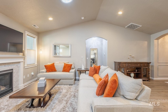 living room featuring a brick fireplace, light hardwood / wood-style flooring, and lofted ceiling