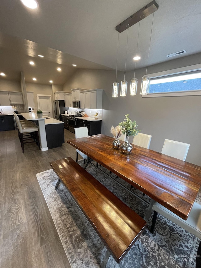 dining space featuring vaulted ceiling and dark hardwood / wood-style floors