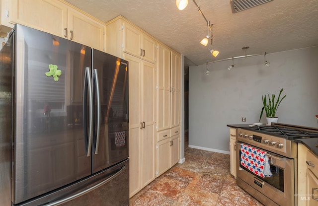 kitchen featuring a textured ceiling, visible vents, appliances with stainless steel finishes, light brown cabinets, and baseboards