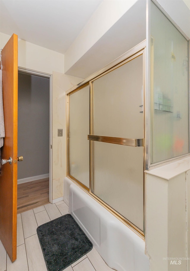 bathroom with tile patterned floors, shower / bath combination with glass door, and baseboards