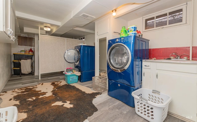 clothes washing area with laundry area, wood finished floors, and visible vents