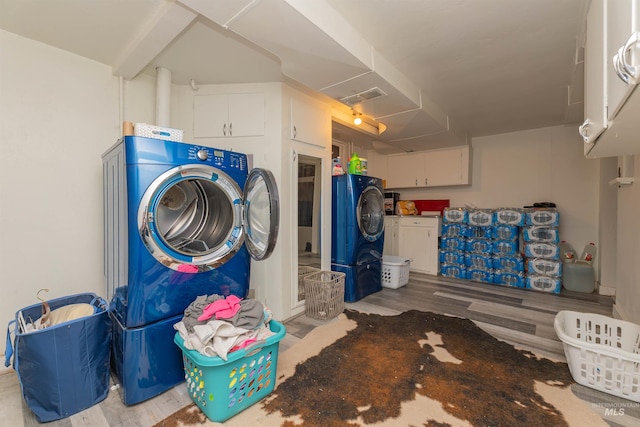 washroom with cabinet space, visible vents, washing machine and dryer, and wood finished floors