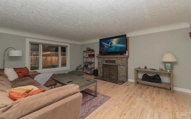 living room featuring baseboards, a textured ceiling, hardwood / wood-style floors, and a fireplace