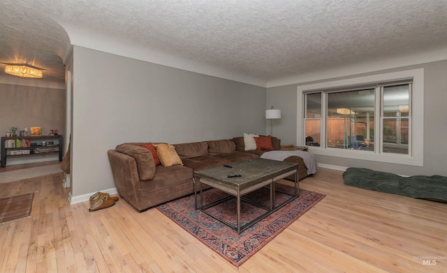 living area with wood-type flooring, baseboards, and a textured ceiling