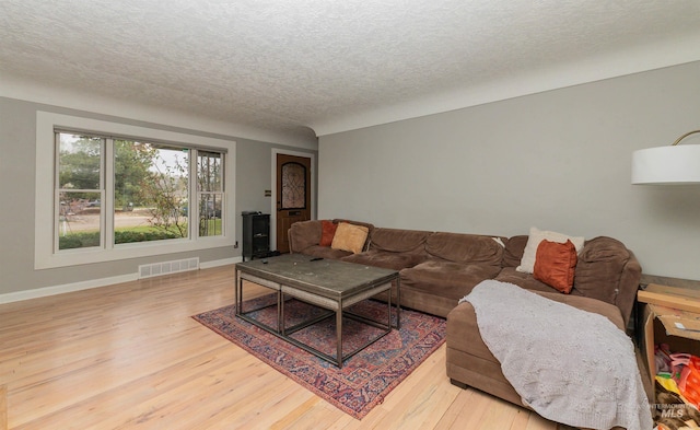 living room featuring light wood finished floors, visible vents, baseboards, and a textured ceiling