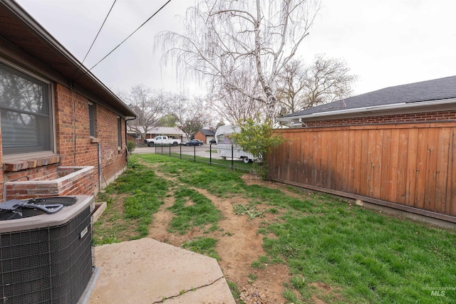 view of yard with central air condition unit and fence