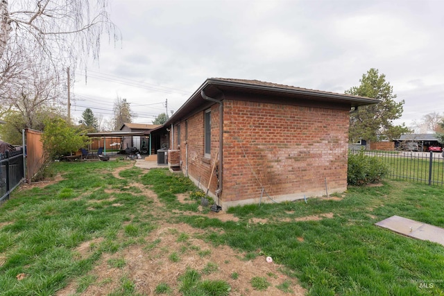 view of property exterior featuring brick siding, a fenced backyard, a patio, and a yard