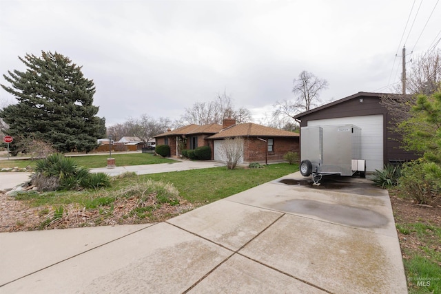 exterior space with an outbuilding, concrete driveway, a garage, and a lawn