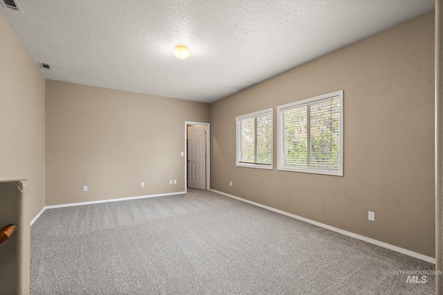 unfurnished room featuring visible vents, carpet, baseboards, and a textured ceiling