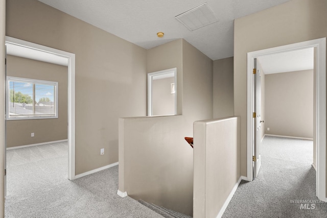 hallway featuring carpet floors, baseboards, an upstairs landing, and visible vents