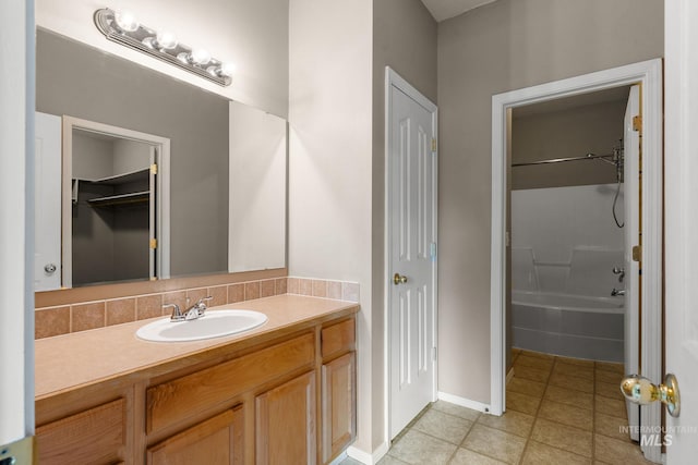 bathroom featuring tile patterned flooring, bathtub / shower combination, vanity, baseboards, and a closet