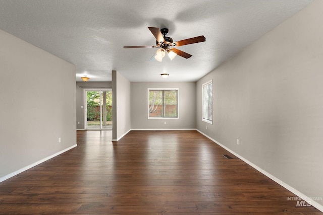 empty room featuring visible vents, baseboards, dark wood-type flooring, a textured ceiling, and a ceiling fan